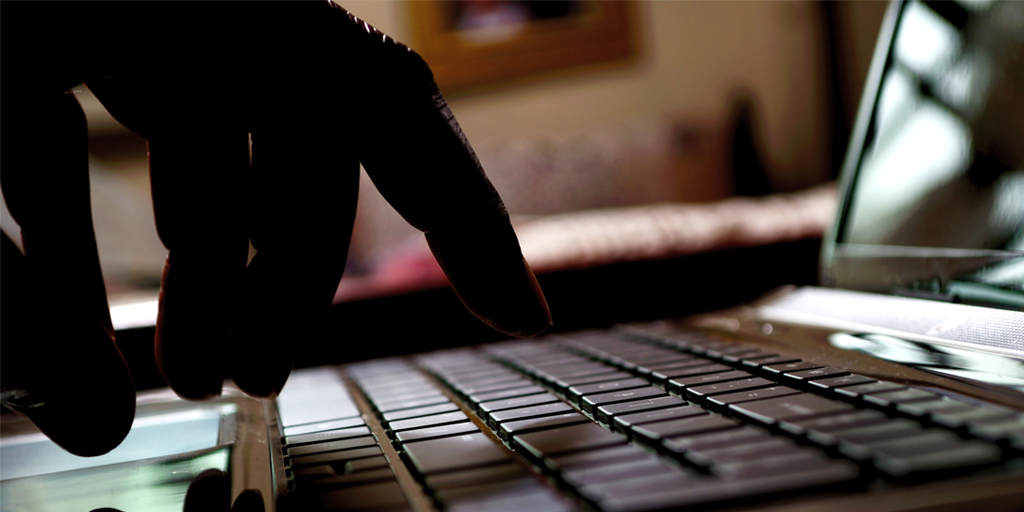 A dark photo of a person's hands typing on a laptop